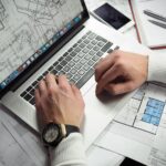 man using turned on macbook pro on white printer papers